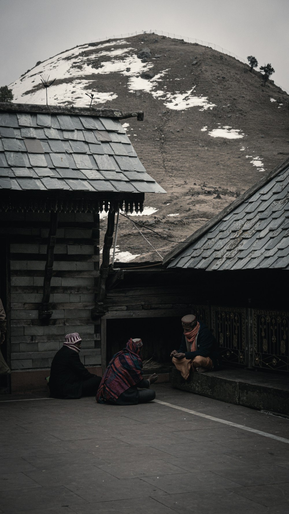 two people sitting on the ground in front of a building