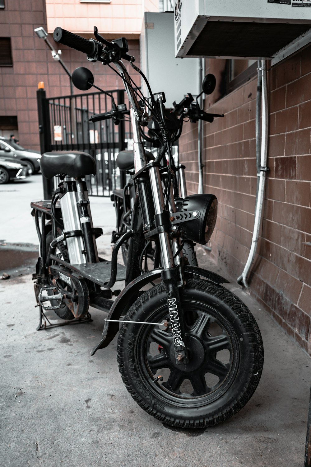 a black scooter parked next to a brick wall