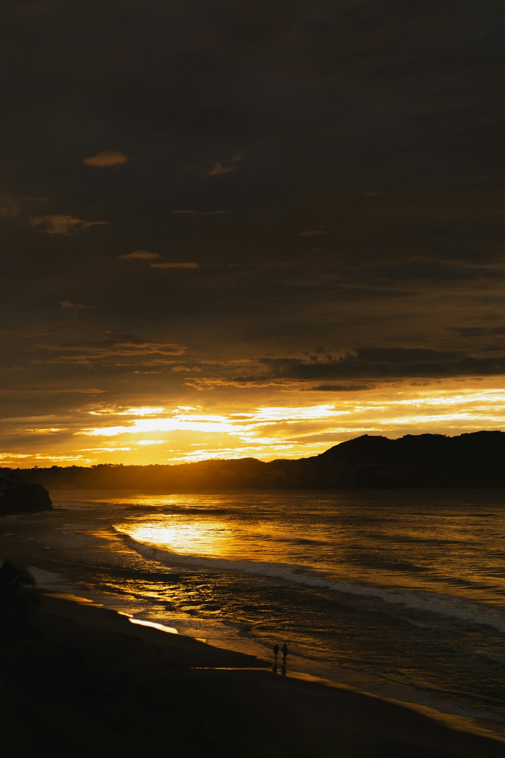 the sun is setting over the ocean and a beach