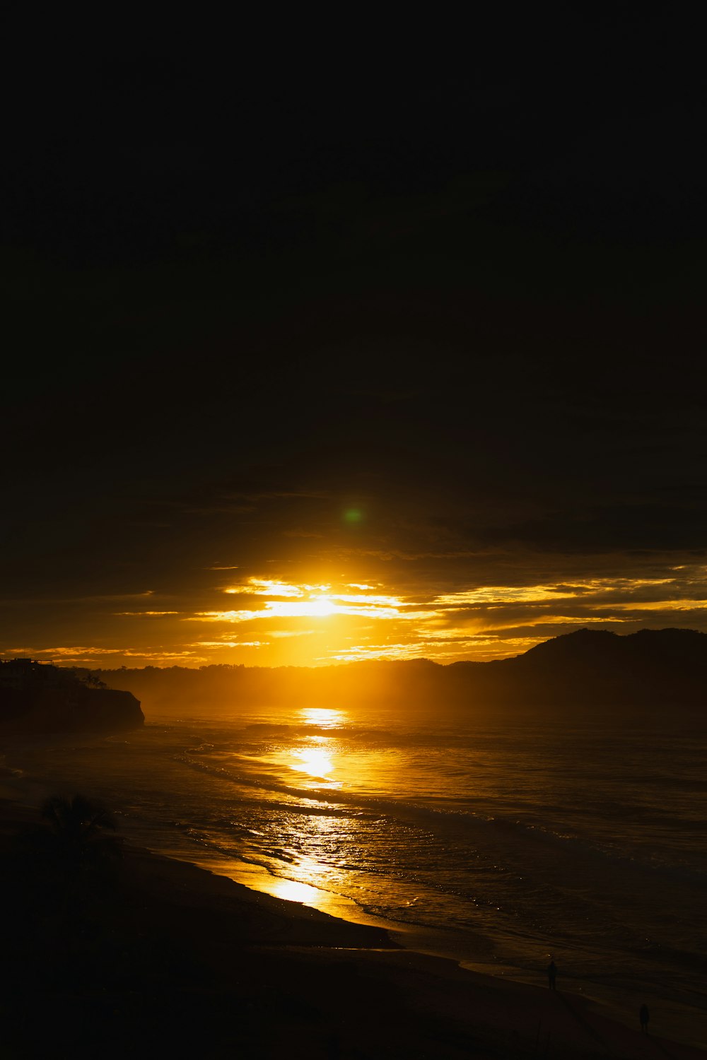 the sun is setting over the ocean on the beach