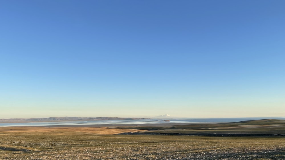 a large open field with a body of water in the distance