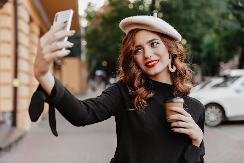 a woman holding a cup of coffee and a cell phone