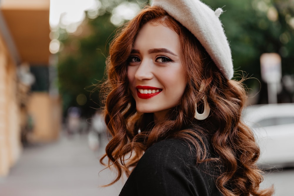 a woman wearing a white hat and smiling at the camera