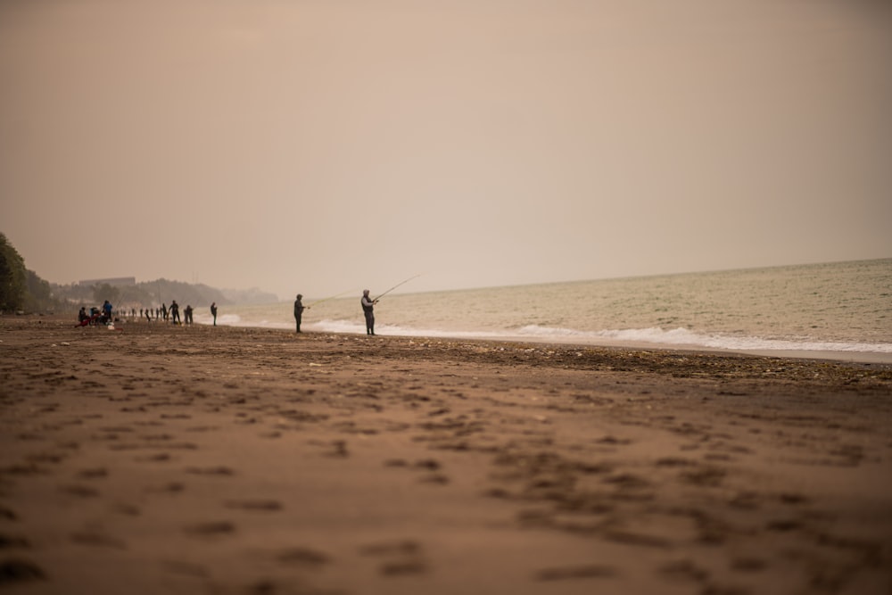 um grupo de pessoas em pé em cima de uma praia de areia