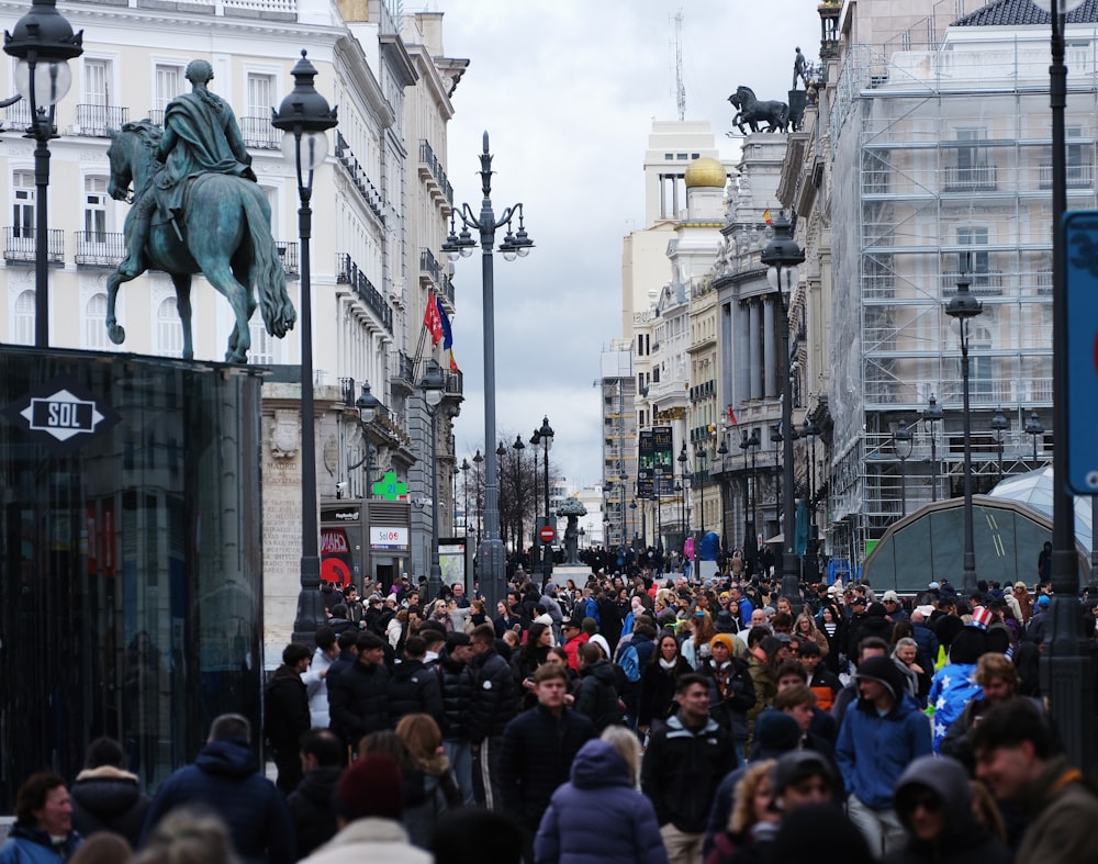 a crowd of people walking down a street next to tall buildings