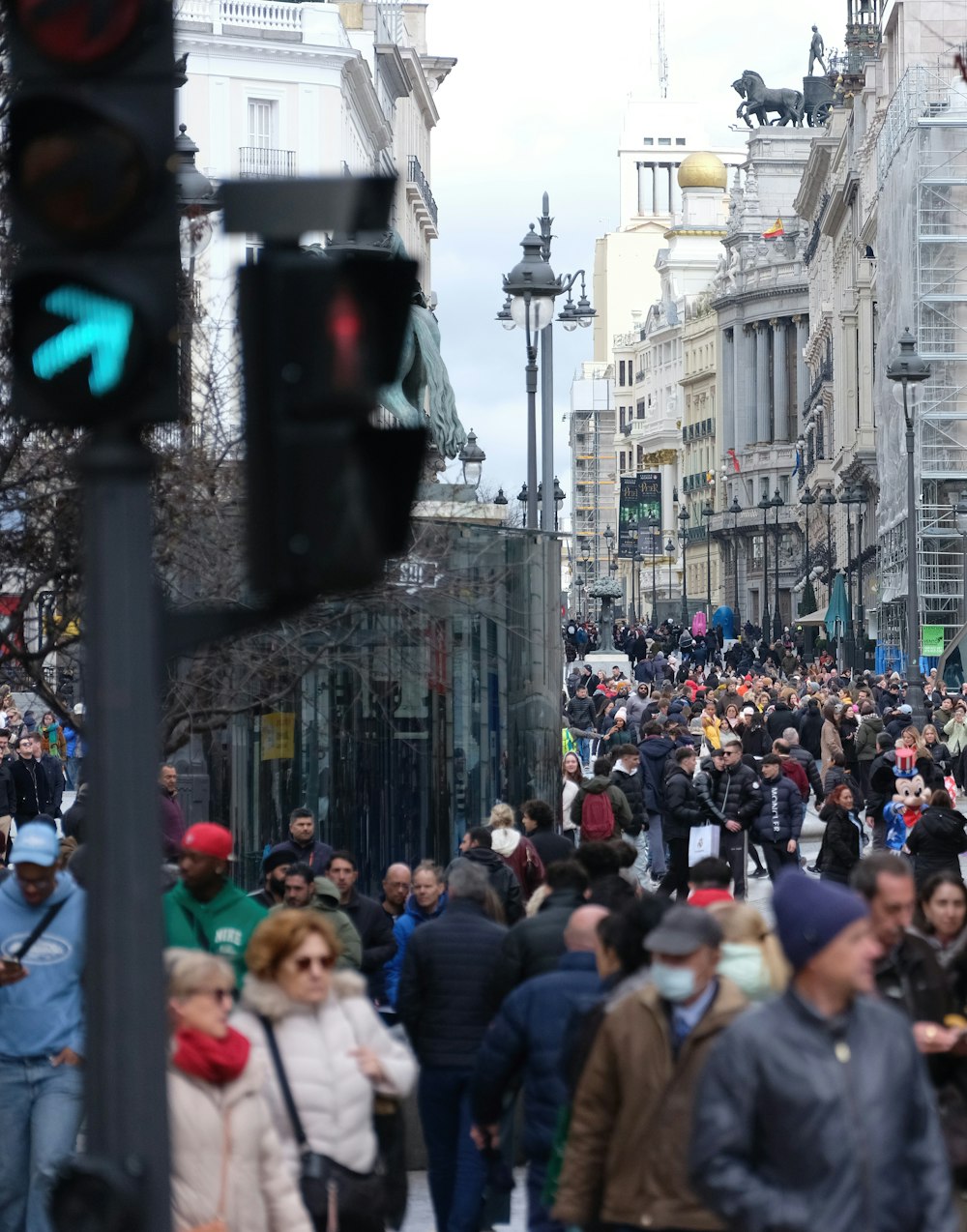 a crowd of people walking down a street next to tall buildings