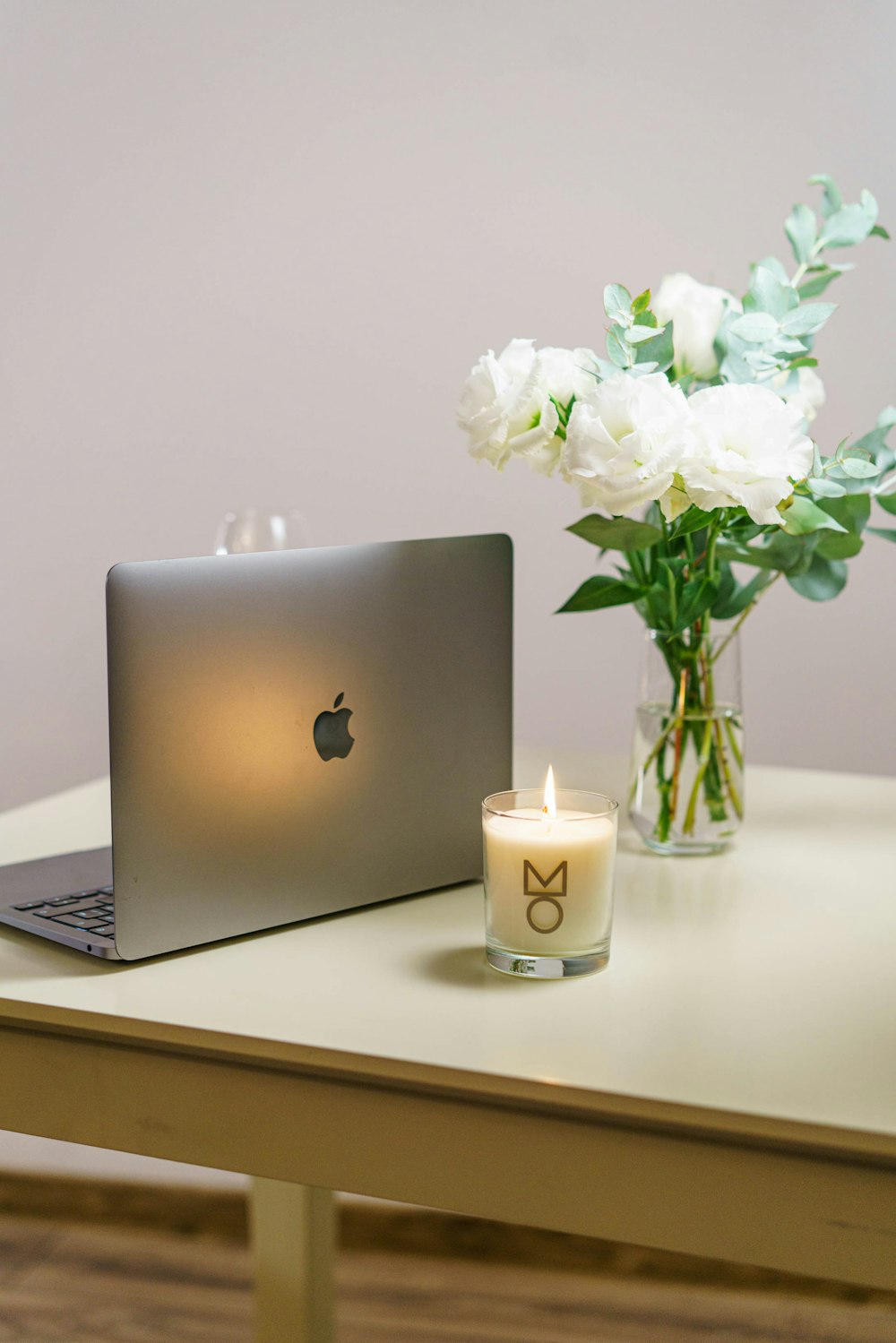 a vase of flowers and a laptop on a table