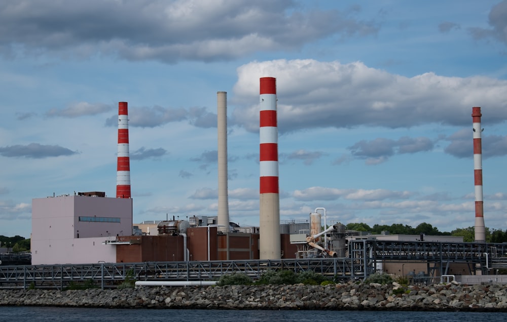 a factory with red and white smoke stacks