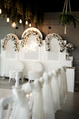 a room with white chairs and flowers on the wall