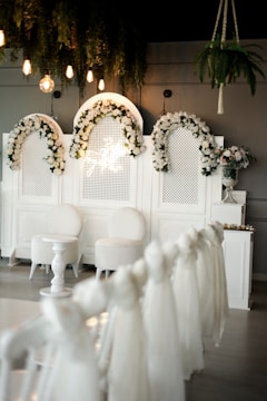 a room with white chairs and flowers on the wall