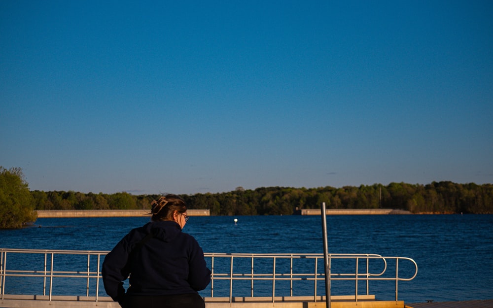 a woman standing on a pier looking at the water