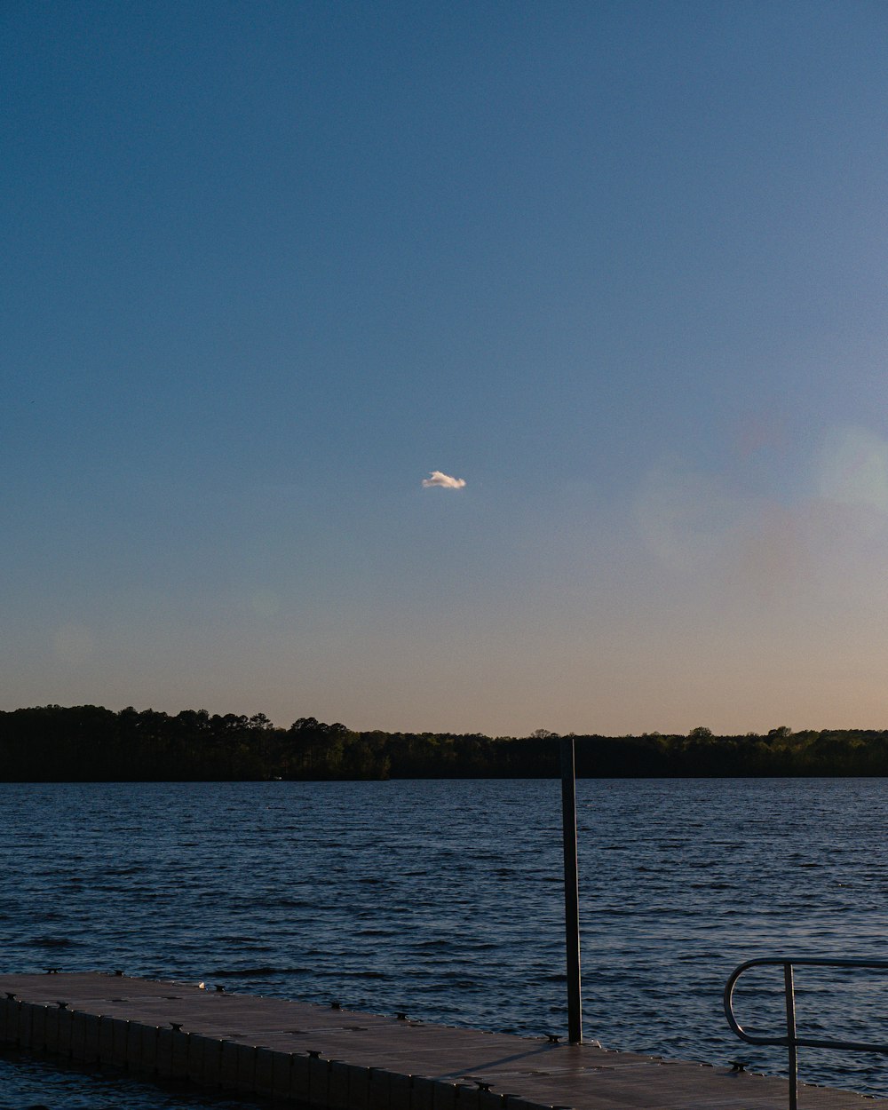 a boat dock on a lake with a small cloud in the sky