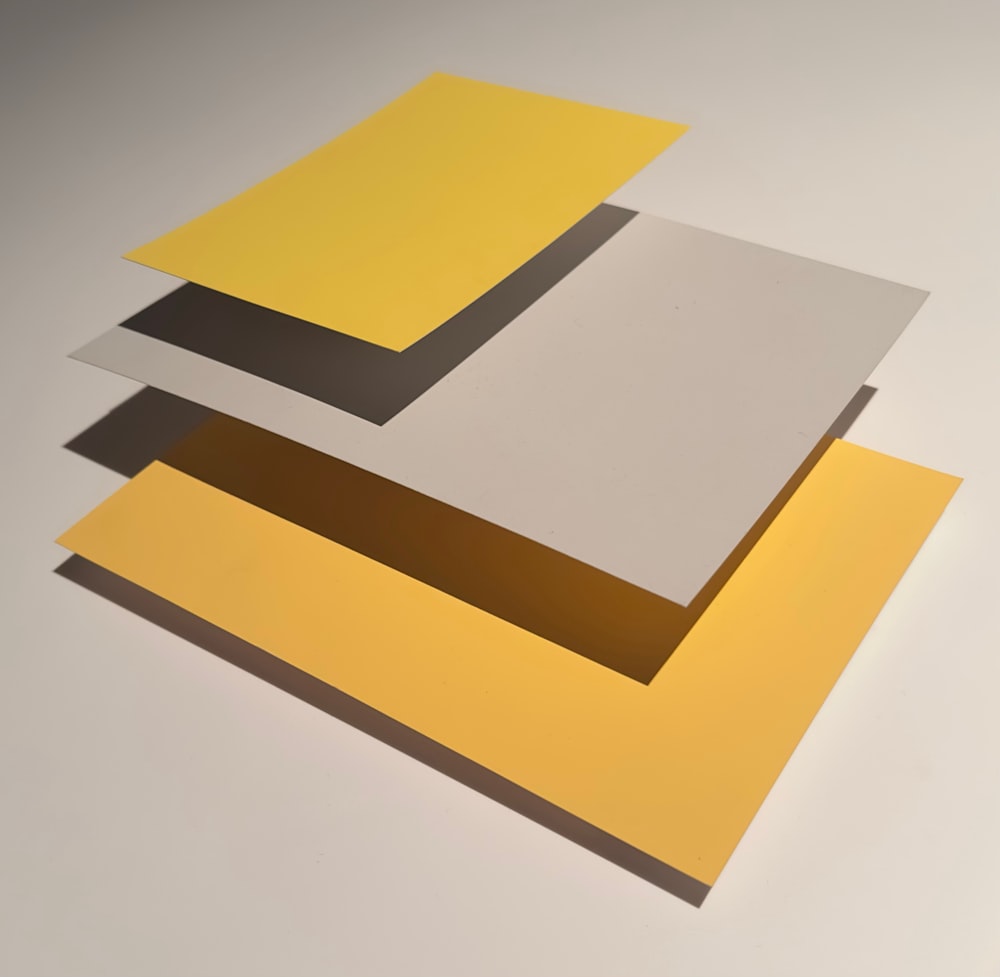 a stack of yellow and grey papers on a white surface