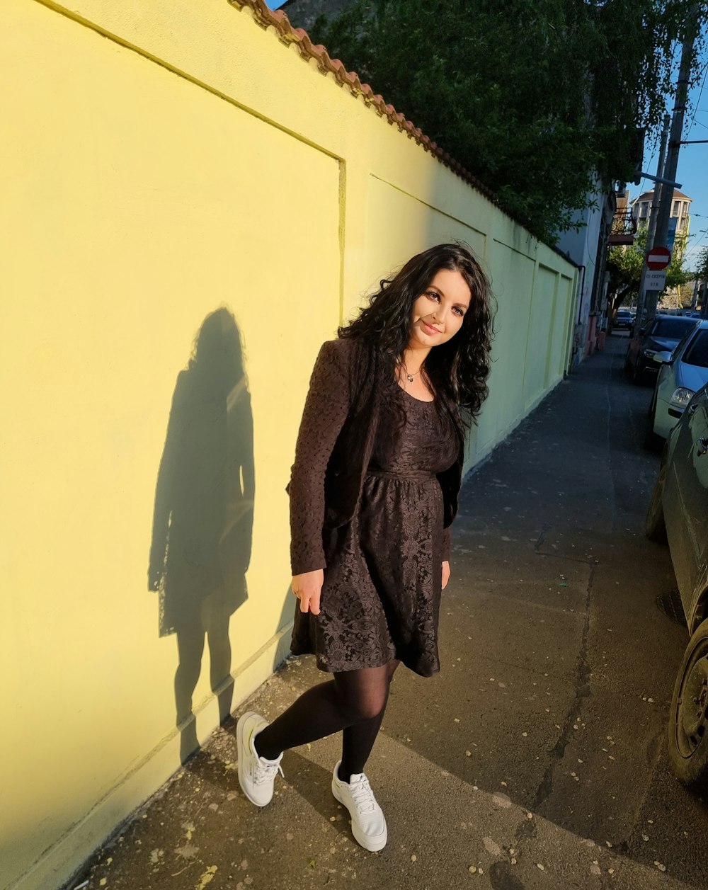 a woman standing next to a yellow wall
