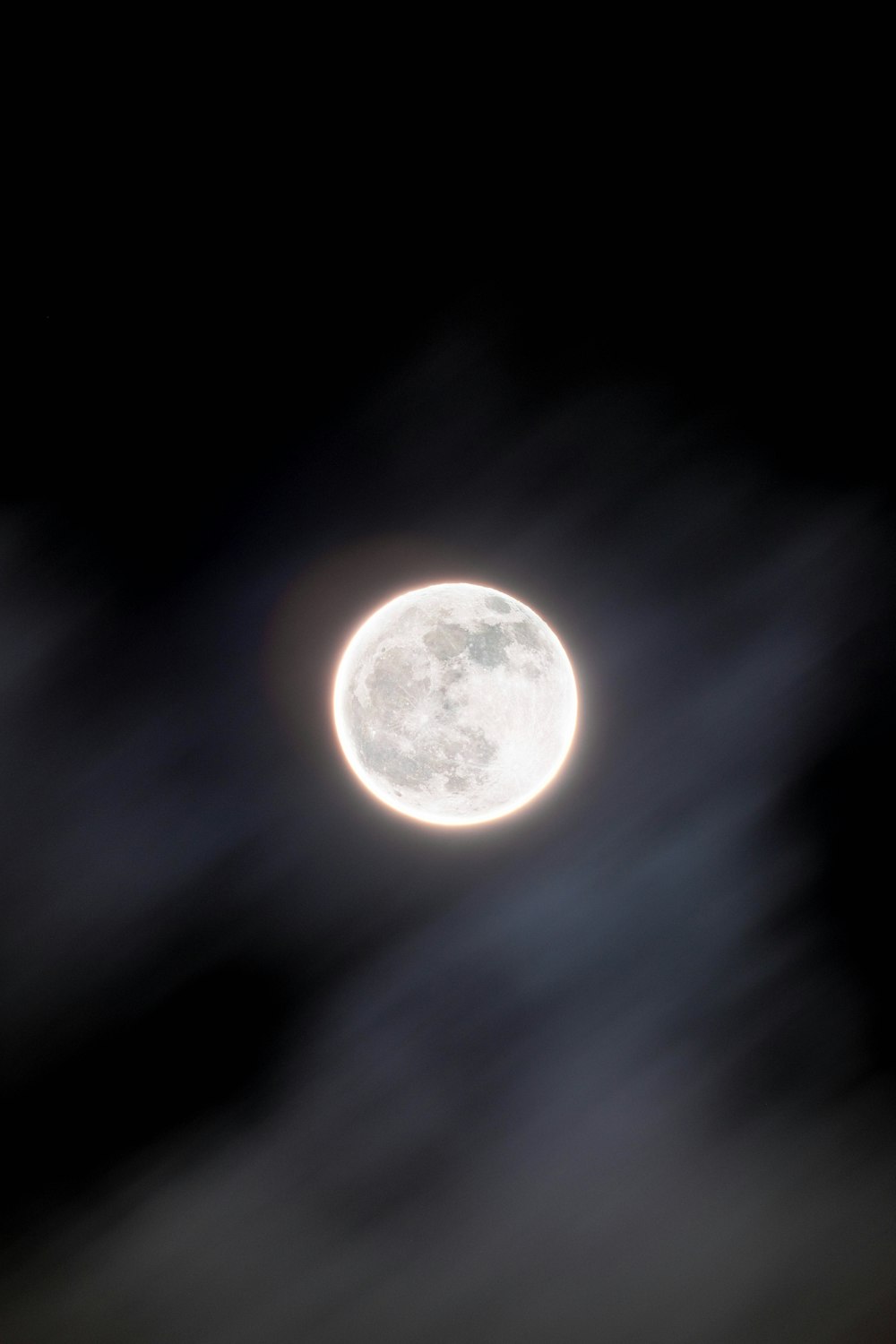 a full moon seen through the clouds in the night sky