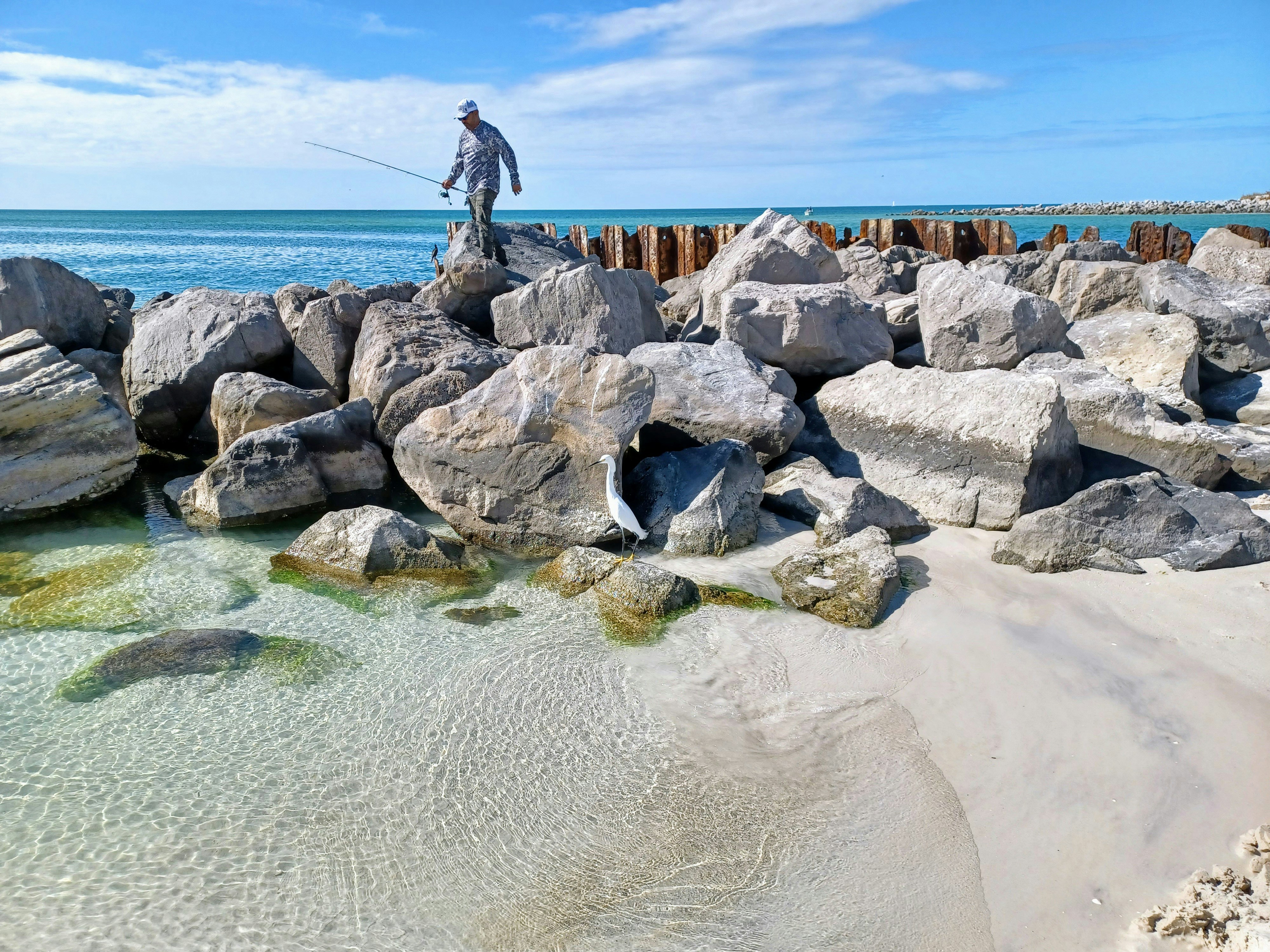 a man standing on top of a pile of rocks next to the ocean