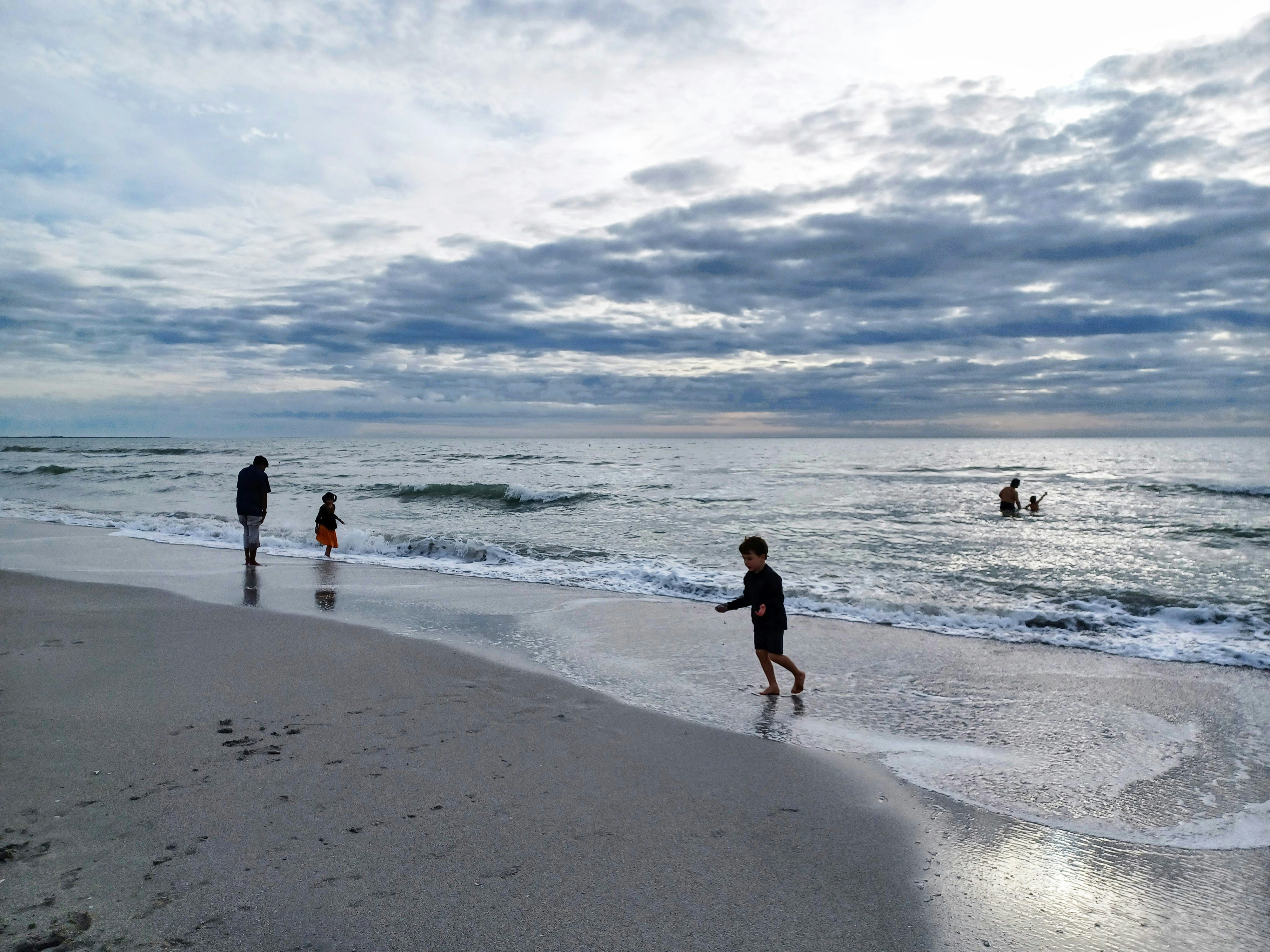 a group of people standing on top of a beach next to the ocean