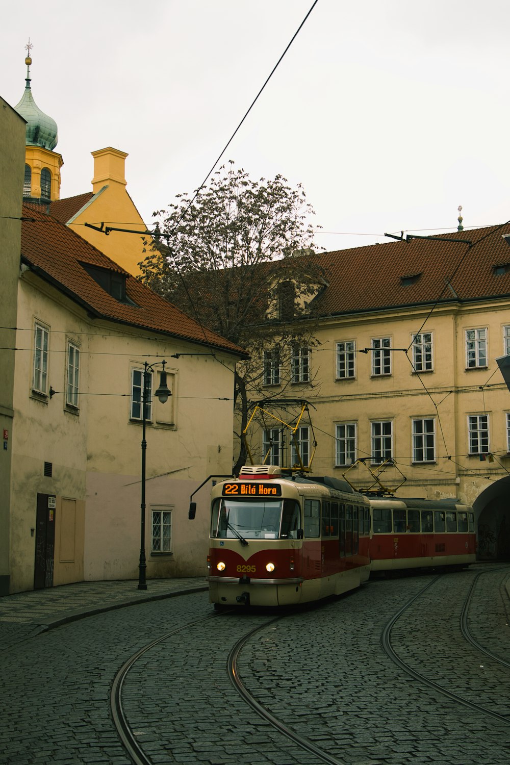 a red and white train traveling past a tall building