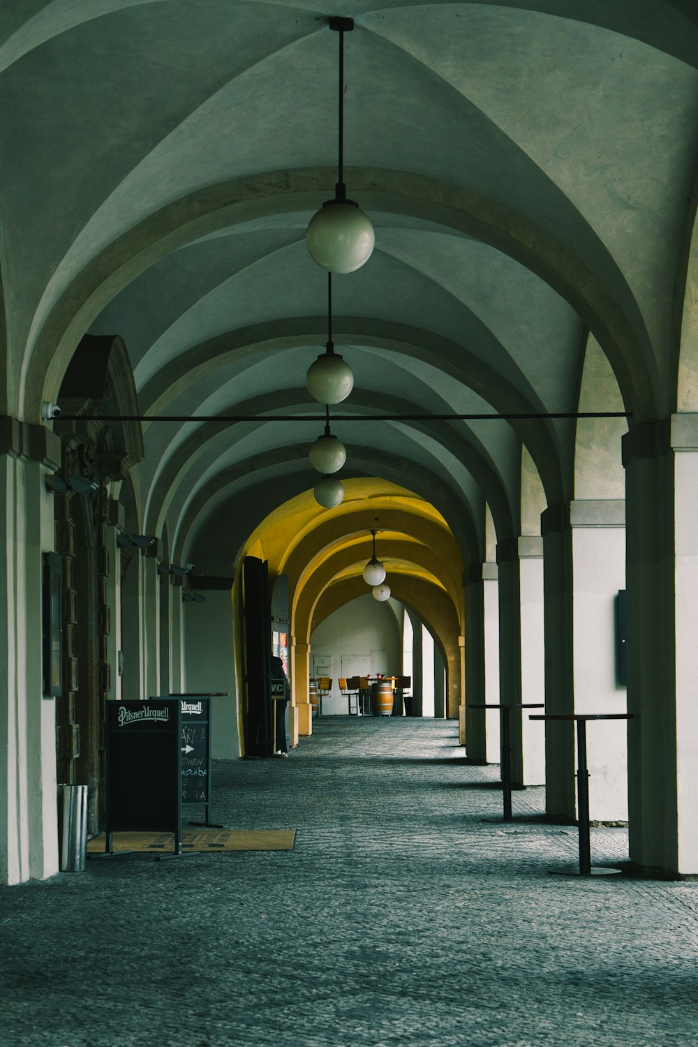 a long hallway with arches and lamps hanging from the ceiling