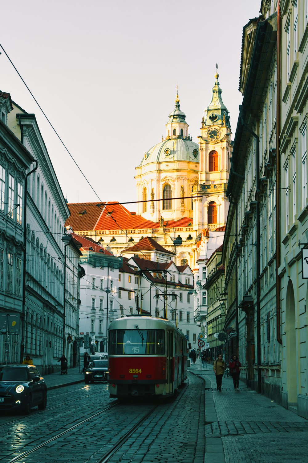 a red and white bus driving down a street next to tall buildings