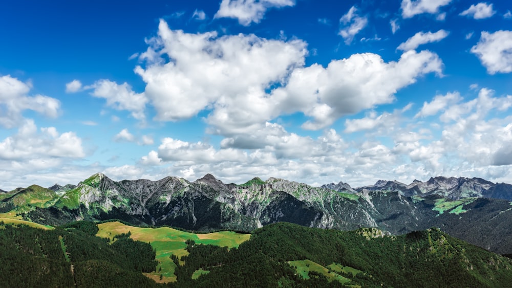 a scenic view of a mountain range under a cloudy blue sky