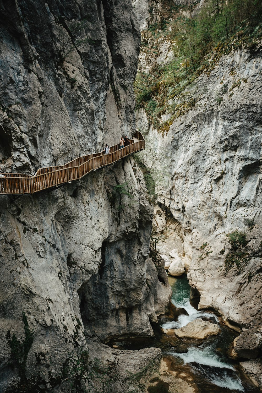 a wooden bridge over a river in a canyon