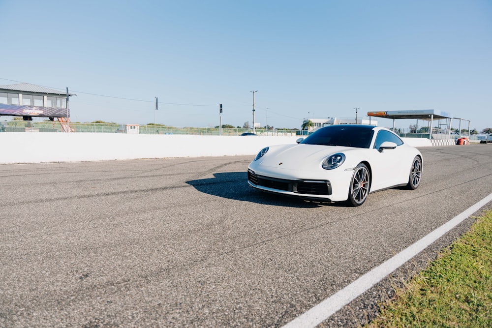 a white sports car driving down a race track