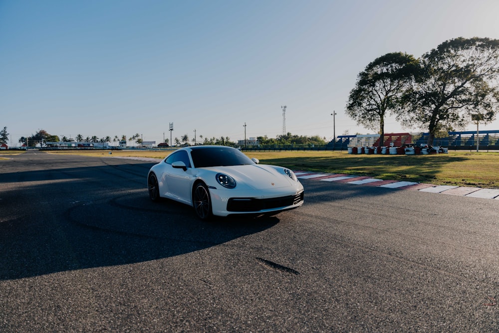 a white sports car driving down a race track