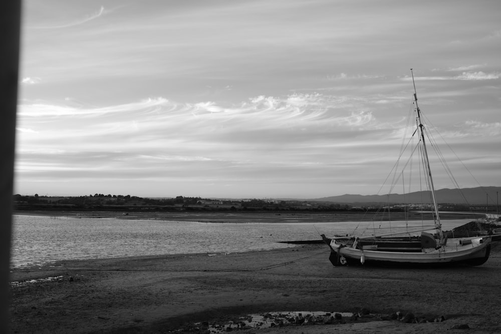 a sailboat sitting on the shore of a body of water