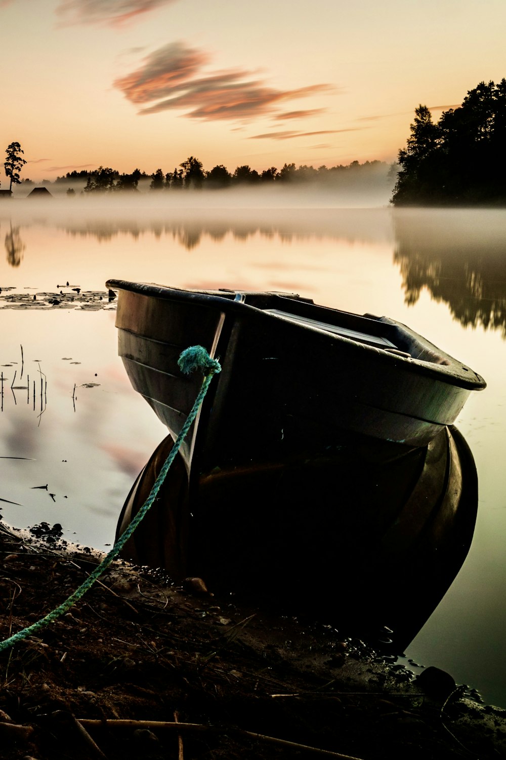 a boat is tied up on the shore of a lake