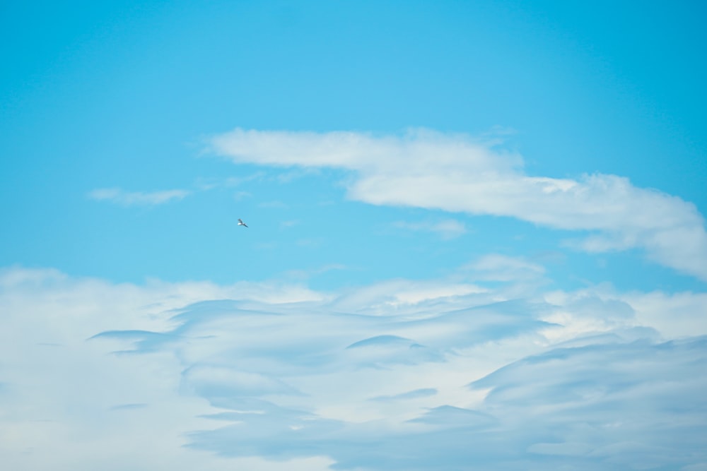 a plane flying through a blue sky with clouds