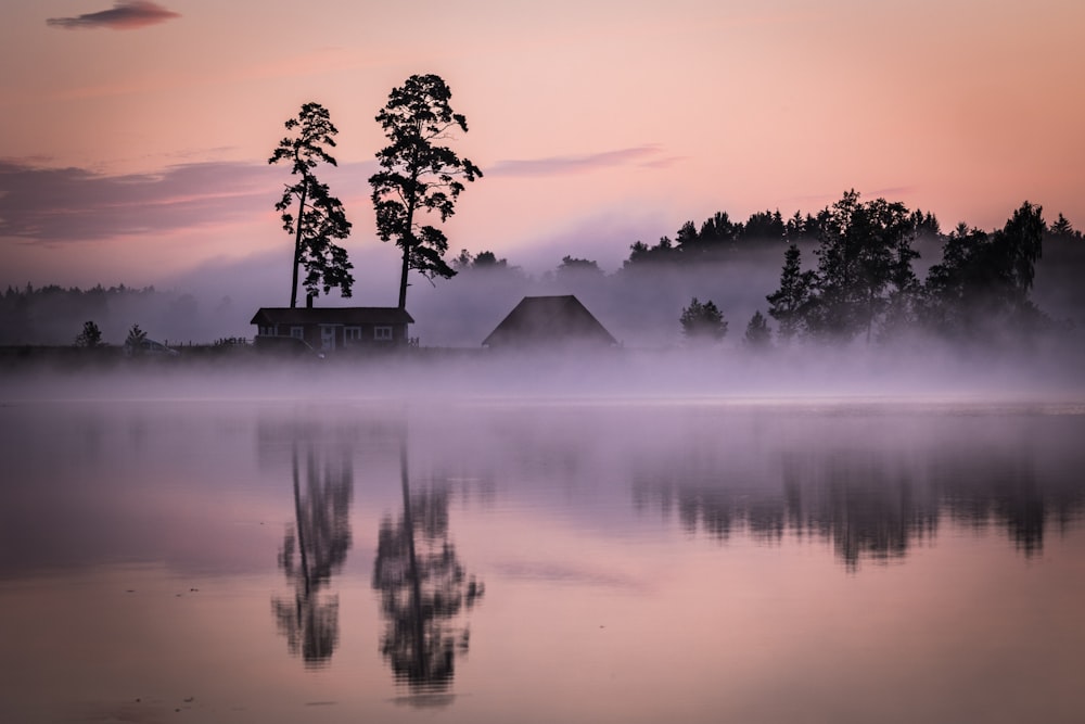 a foggy lake with a house in the distance