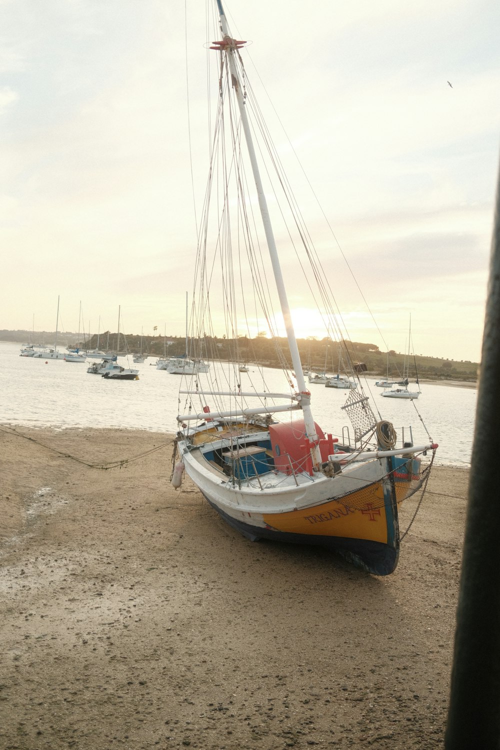 a sailboat on the beach with other boats in the water