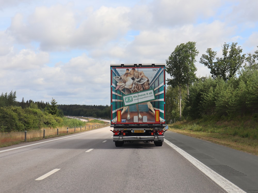 a large truck driving down a road next to a forest