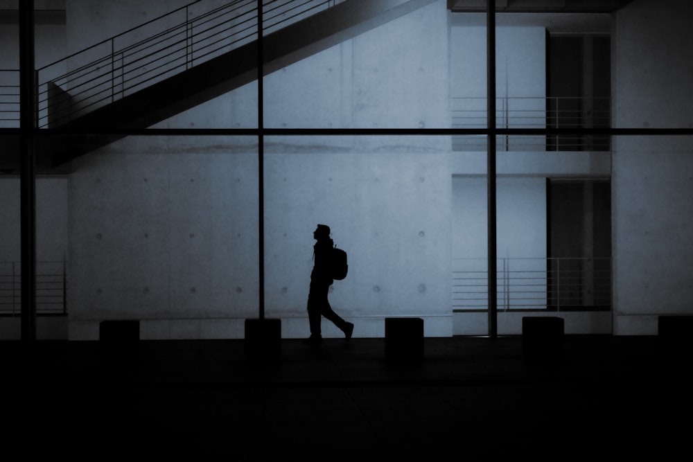 a silhouette of a person walking in front of a building