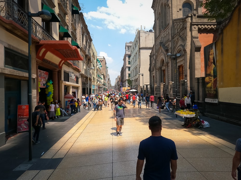 a group of people walking down a street next to tall buildings