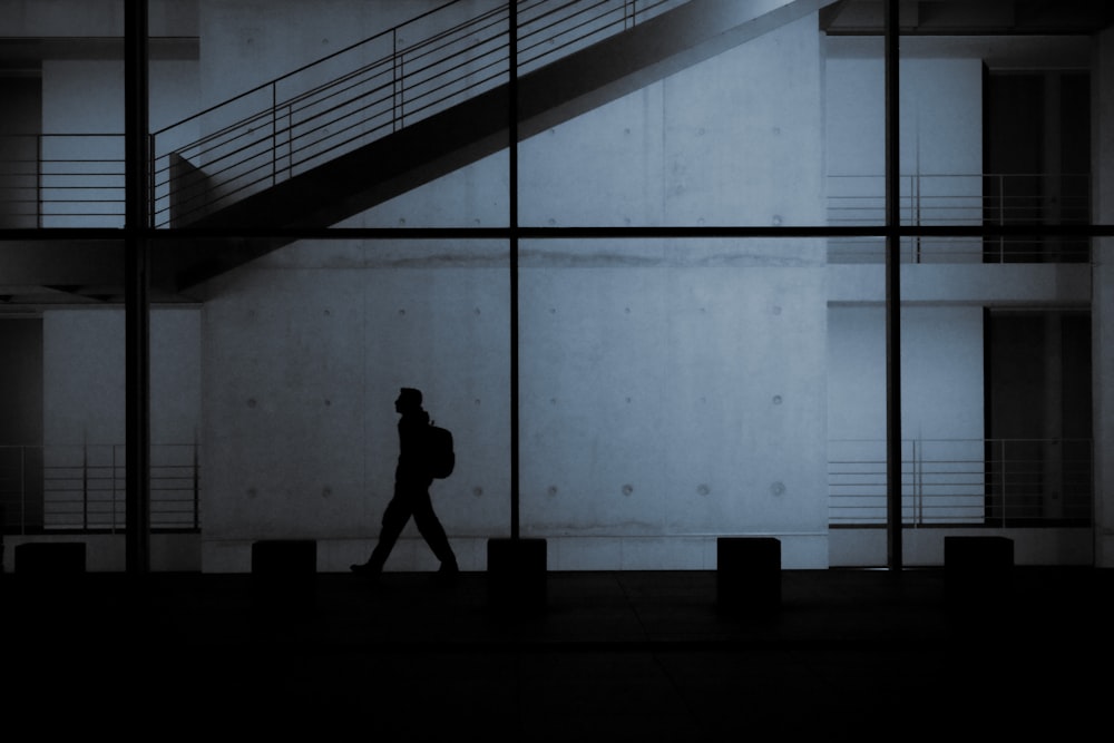 a man walking down a street past a tall building