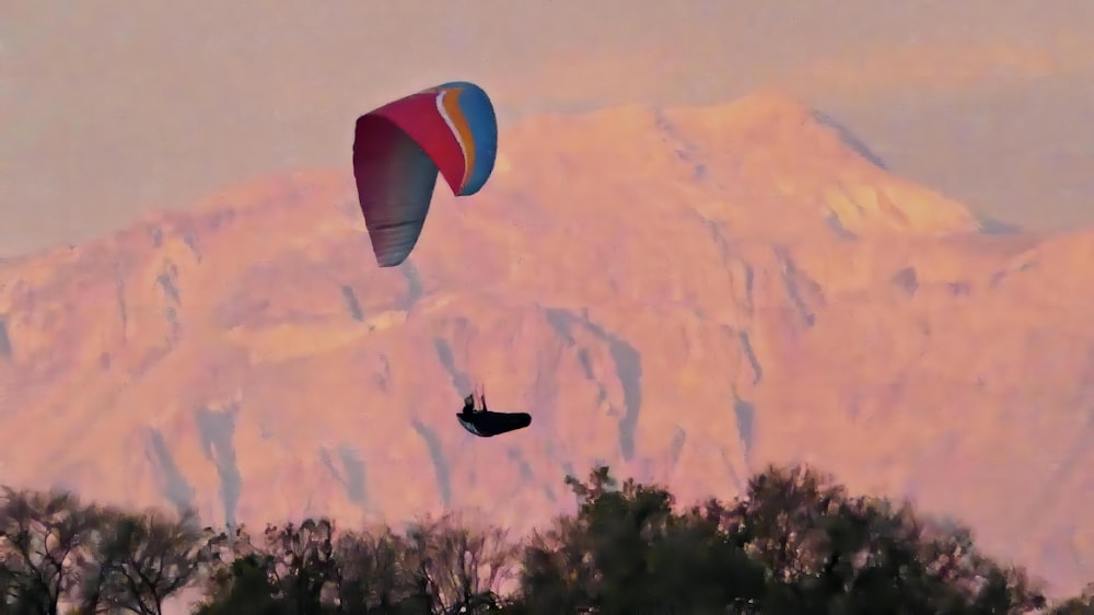 a person parasailing in front of a mountain