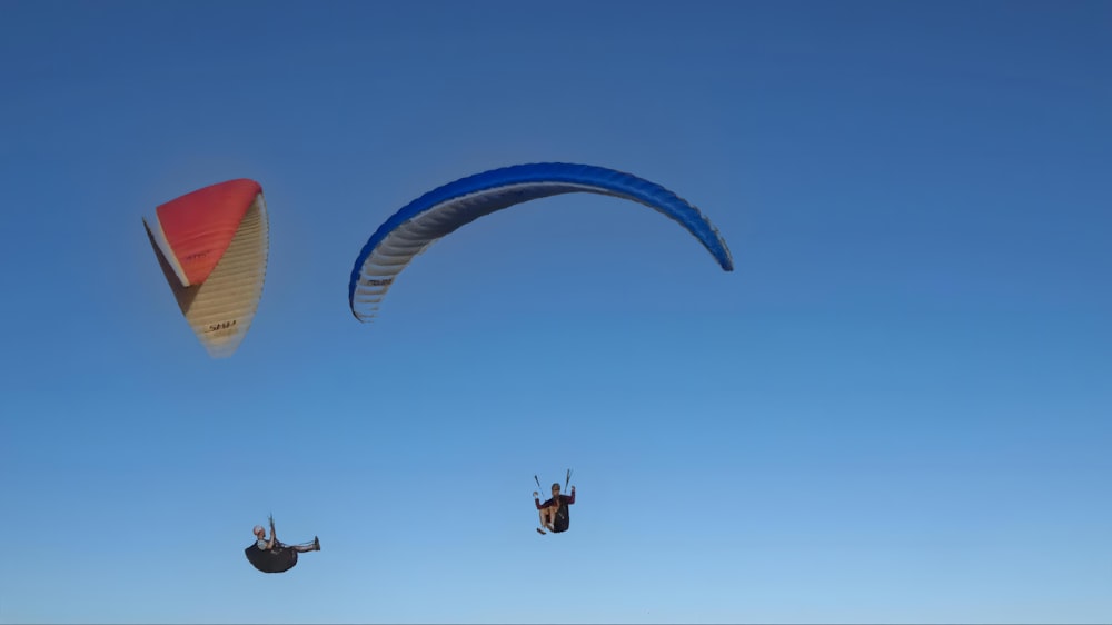 a couple of people that are in the air with parachutes