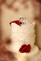 a white wedding cake with red roses on top