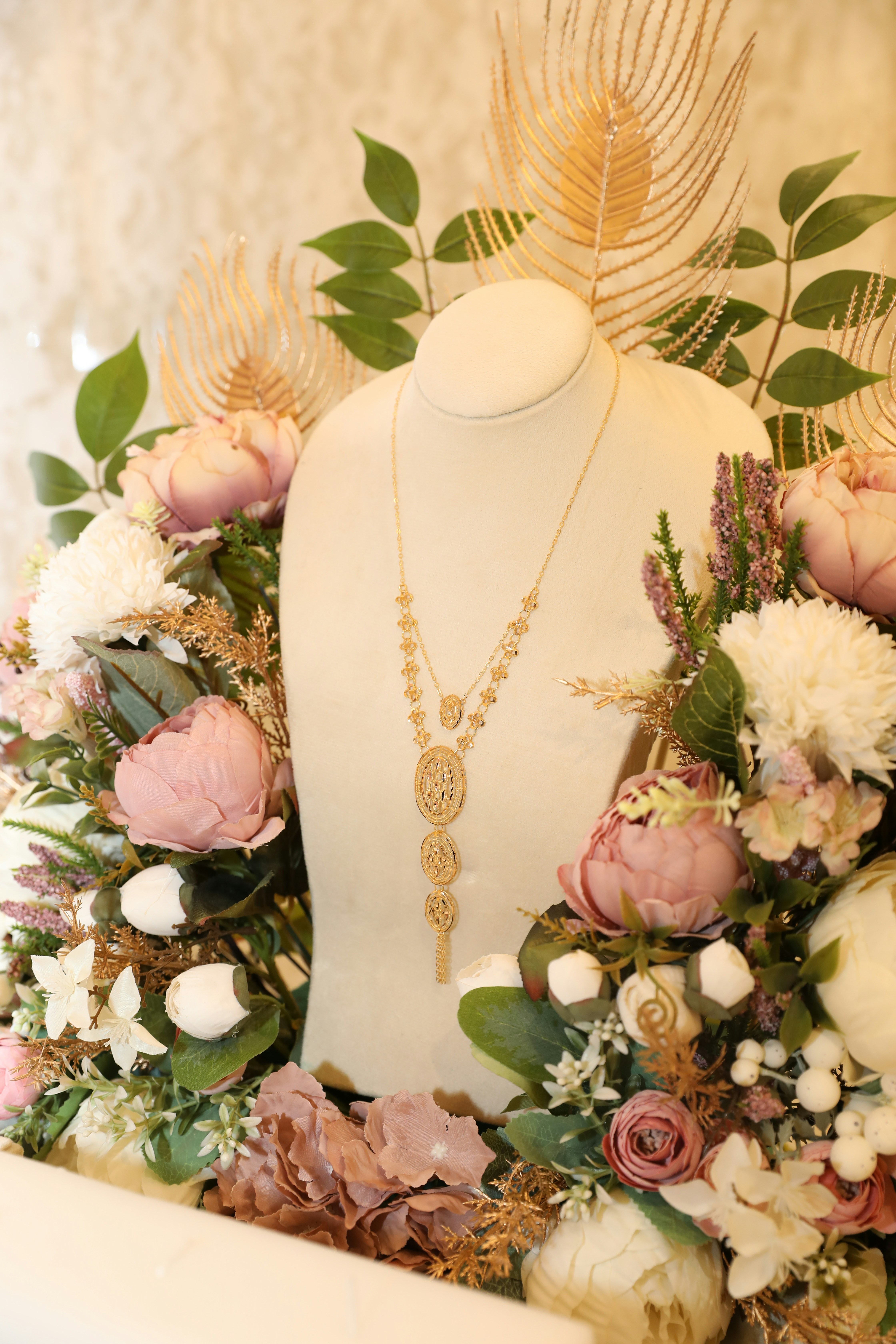 a white mannequin with flowers and a gold necklace