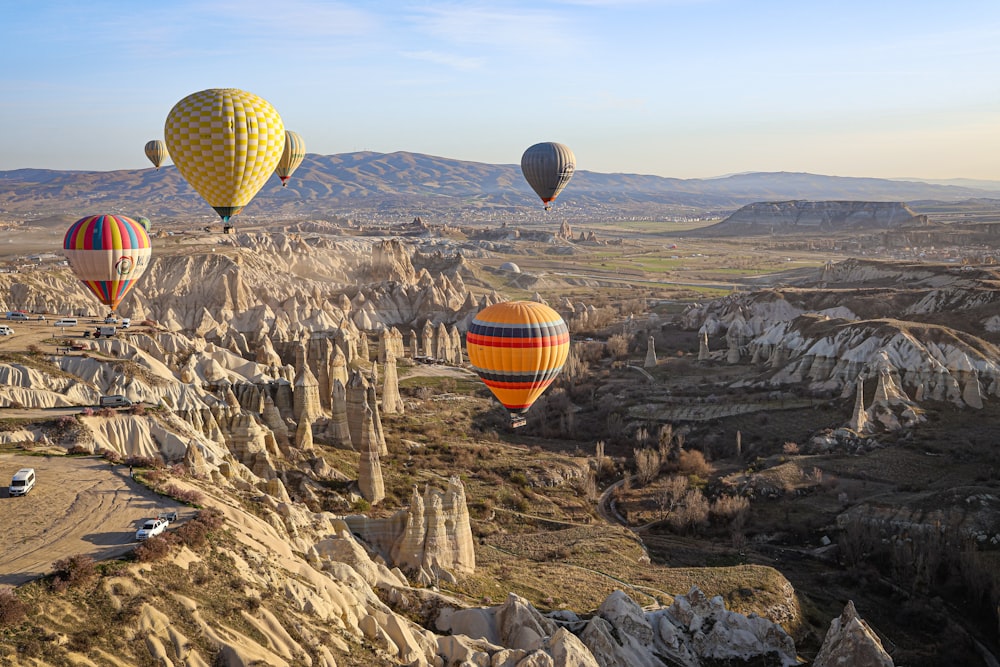 a group of hot air balloons flying over a valley