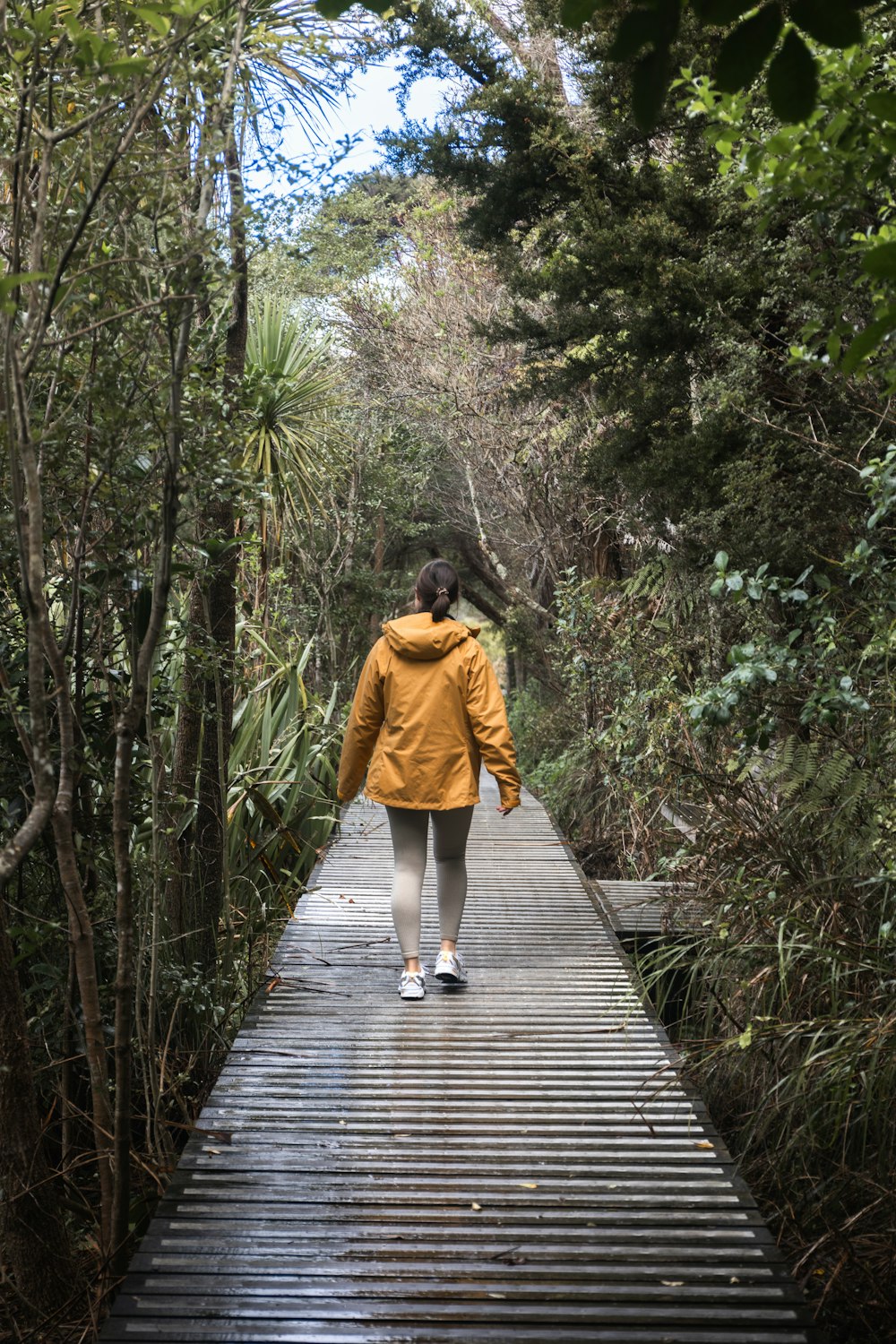 una mujer caminando a través de un puente de madera en el bosque