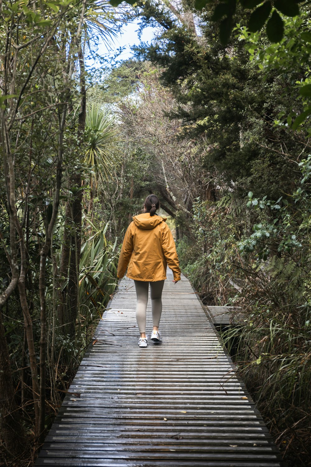 a woman walking across a wooden bridge in the woods