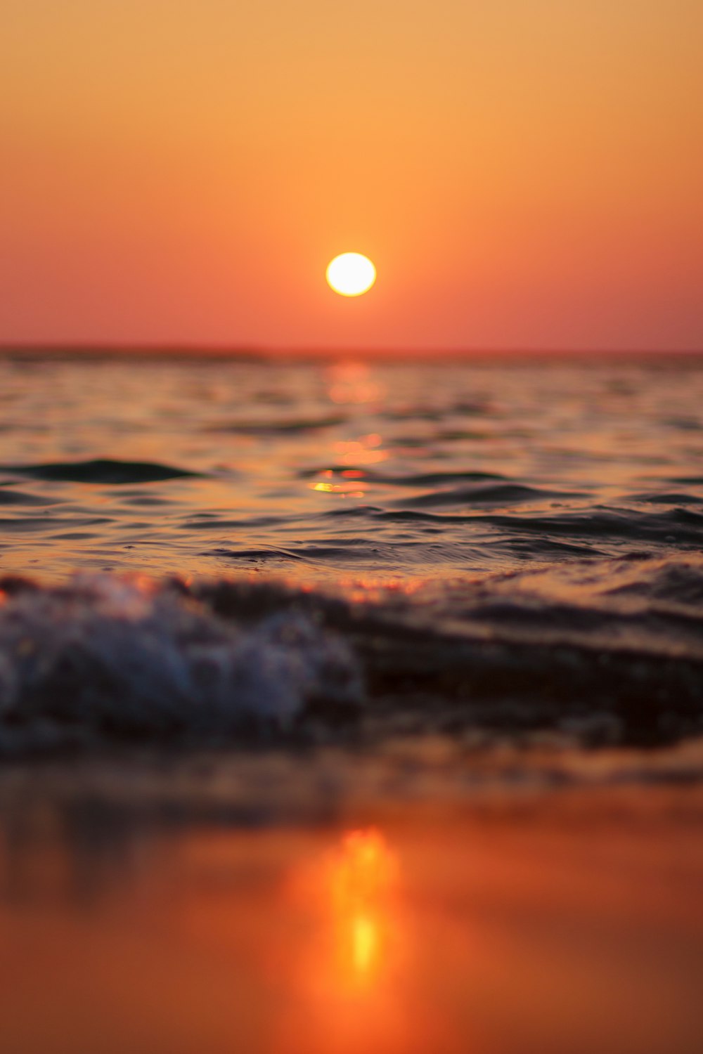 the sun is setting over the water at the beach