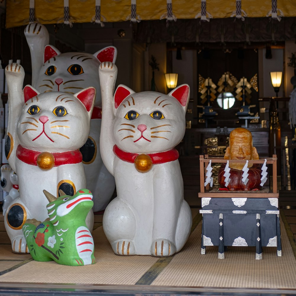 um grupo de gatos de cerâmica sentados em cima de uma mesa