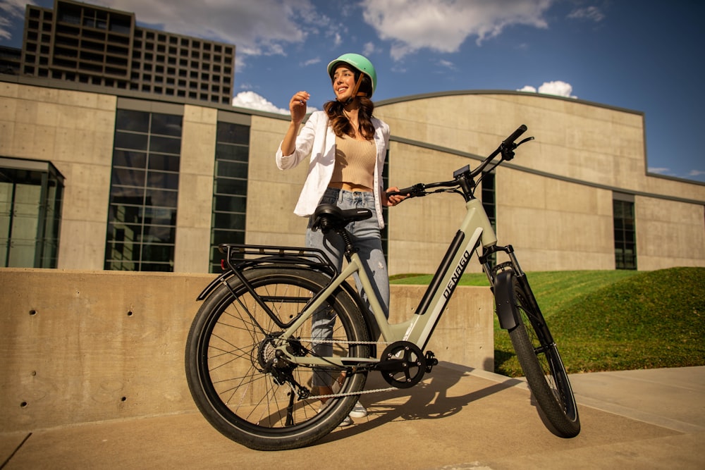 a woman standing next to a bike in front of a building