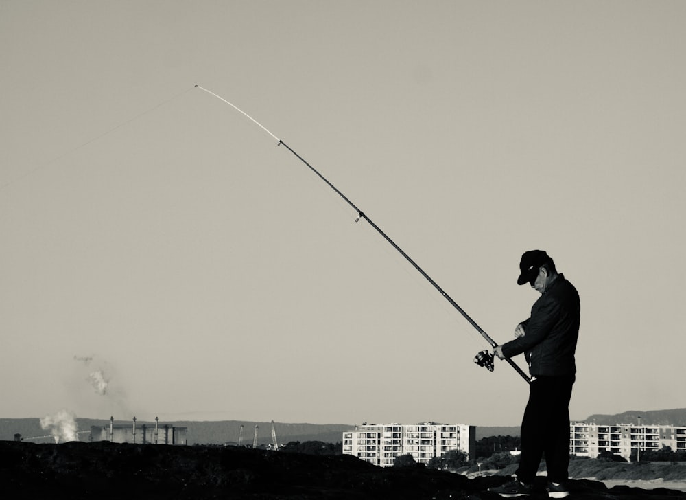 a man standing on top of a hill holding a fishing pole