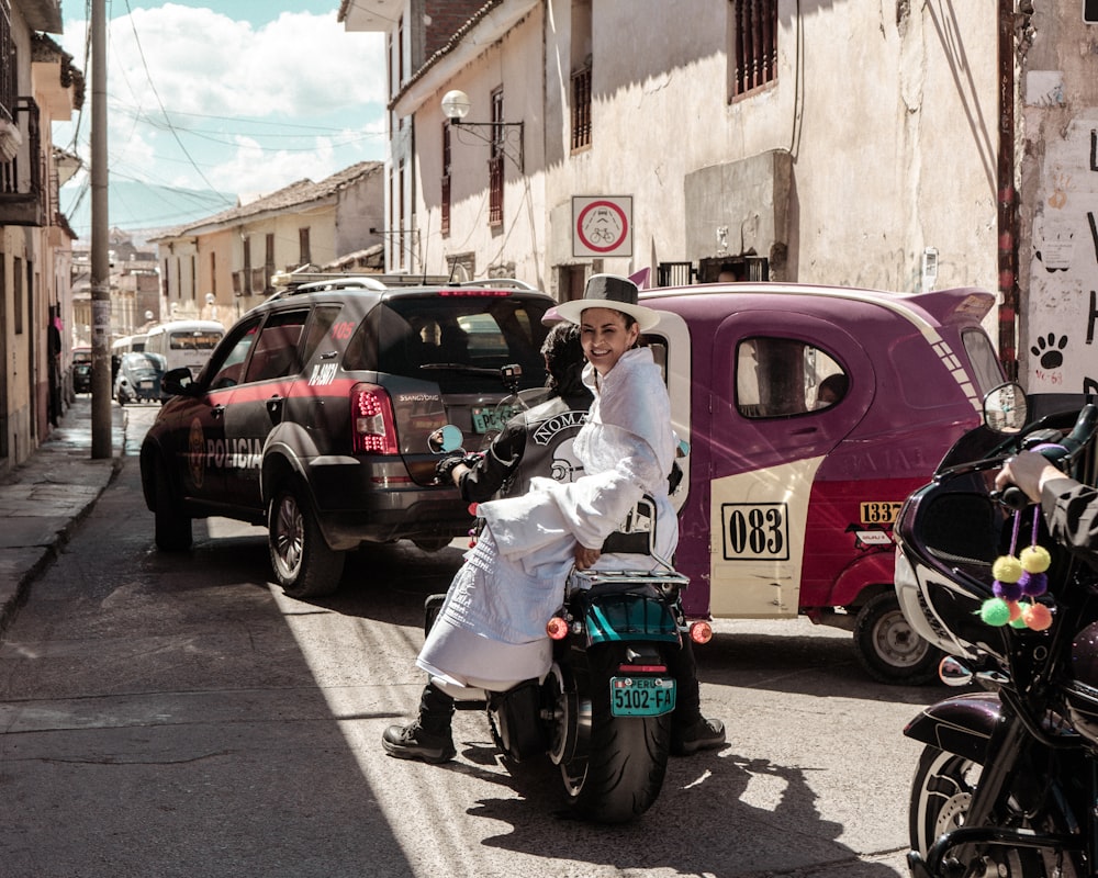 a man riding a motorcycle down a street next to parked cars