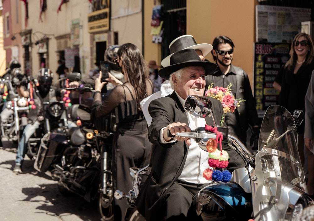 a man riding a motorcycle down a street next to a crowd of people